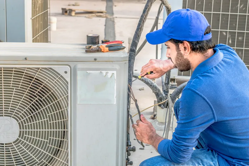 A worker repairs an AC unit in Tavares