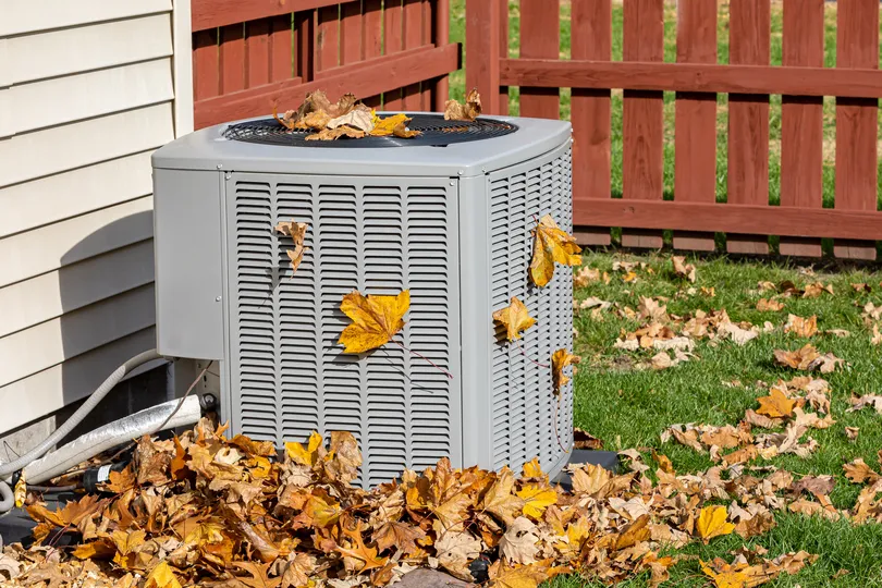 fall leaves on ac unit in backyard with fence