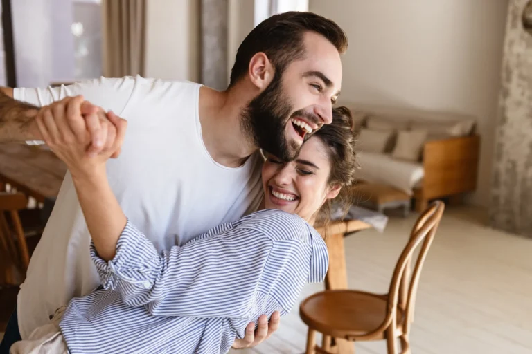 Happy homeowners who are dancing together in their home