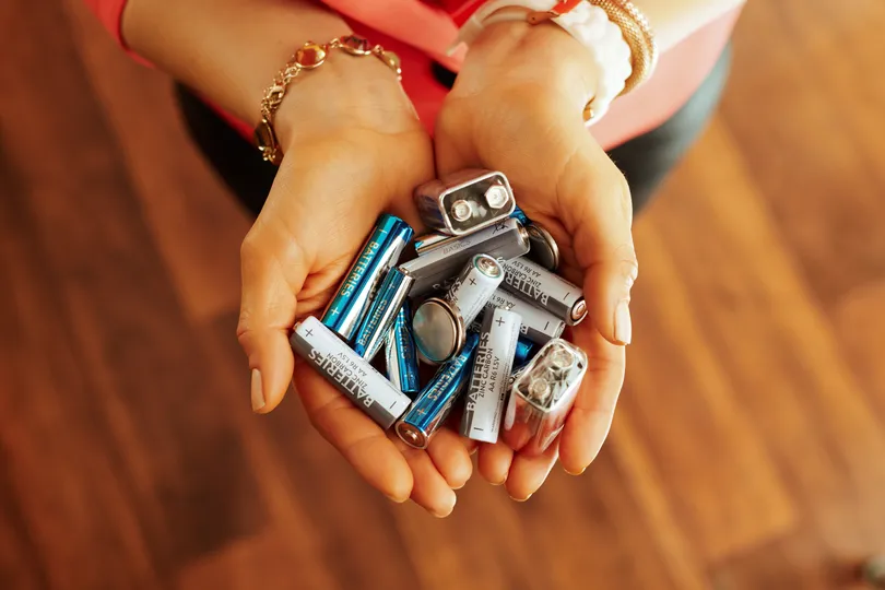 woman with bracelets holding old batteries