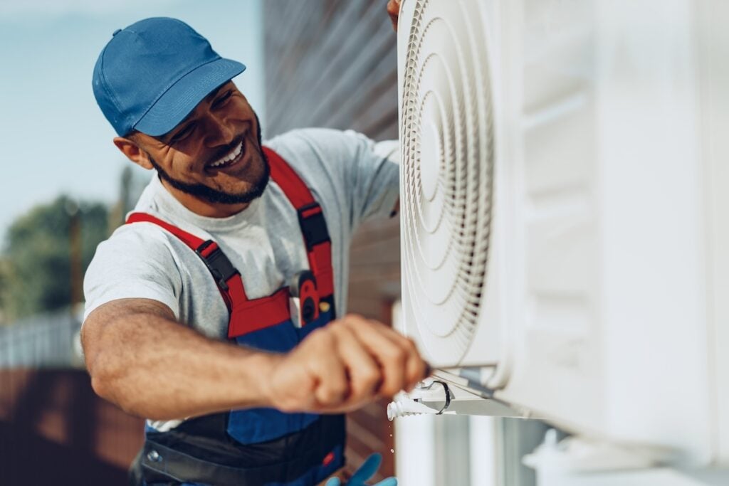 Young man repairman checking an outside air conditioner unit close up