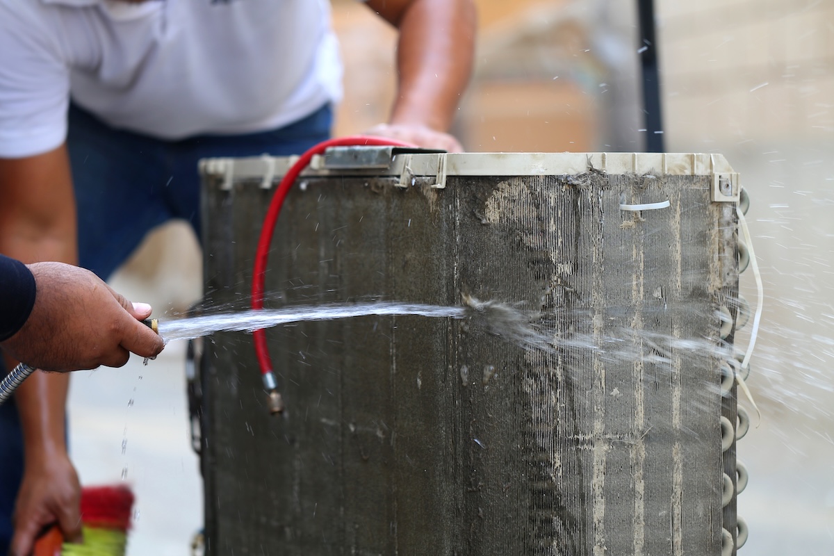 Worker to cleaning coil cooler of air conditioner by water for clean a dust on the wall in customer home when maintenance service