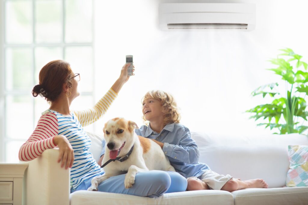 Mother and child with air conditioner remote control. Comfortable temperature at family home. Cooling and heating device. Mom and kid on couch under cold breeze. Air conditioning on hot summer day. indoor air quality testing