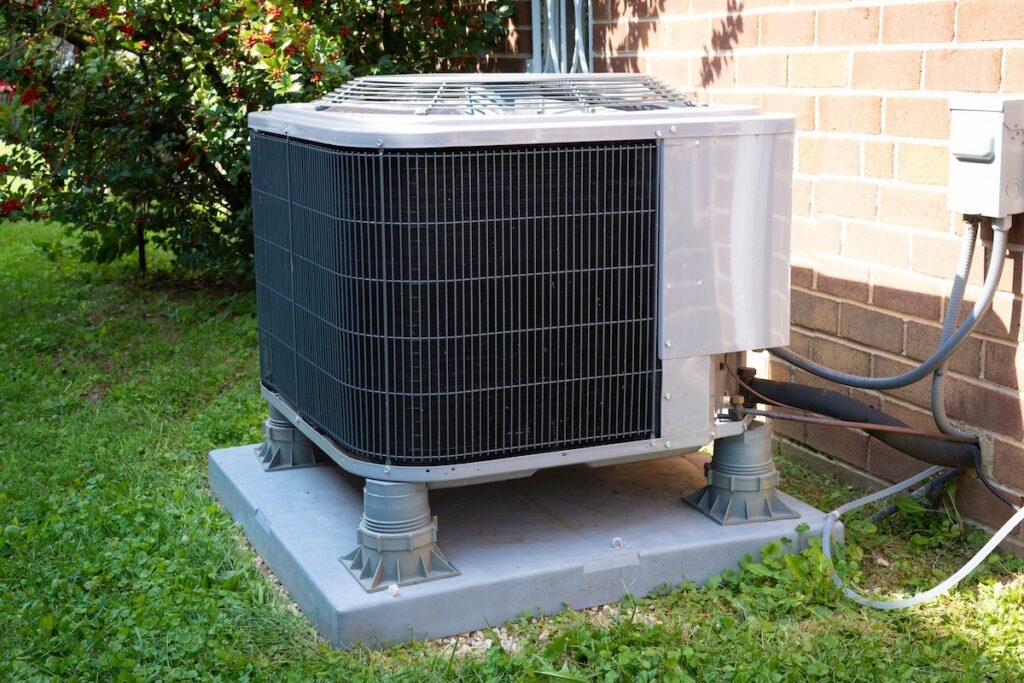HVAC Air Conditioning Unit on concrete slab with new construction brick house garage air conditioner
