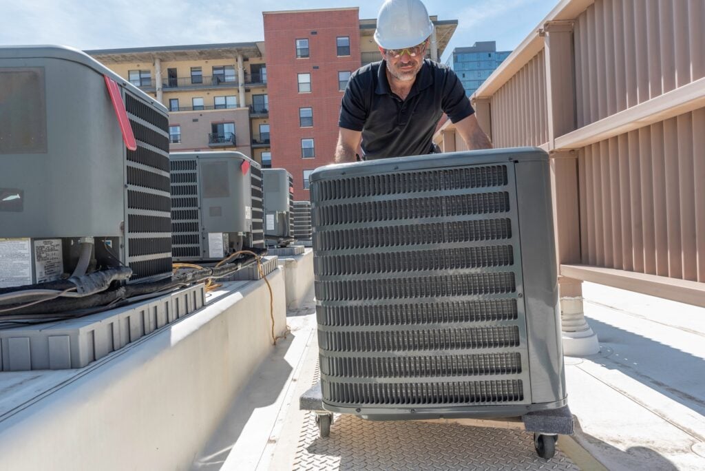 Hvac technician rolling a new air conditioner for an install