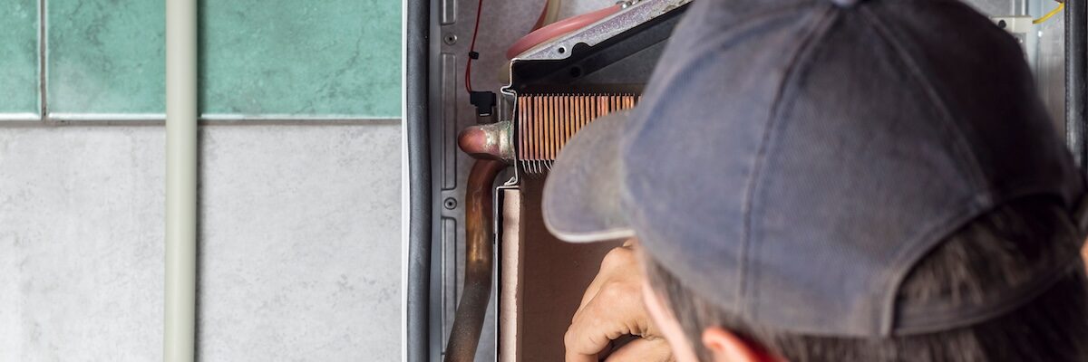 The master sets up a gas boiler, which weighs on the wall. The front dashboard is open. The removal and installation of gas nozzles for gas supply.