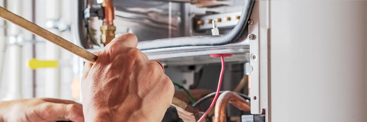The master sets up a gas boiler, which weighs on the wall. The front dashboard is open. Using a brush and an industrial vacuum cleaner, cleaning from dirt and dirt