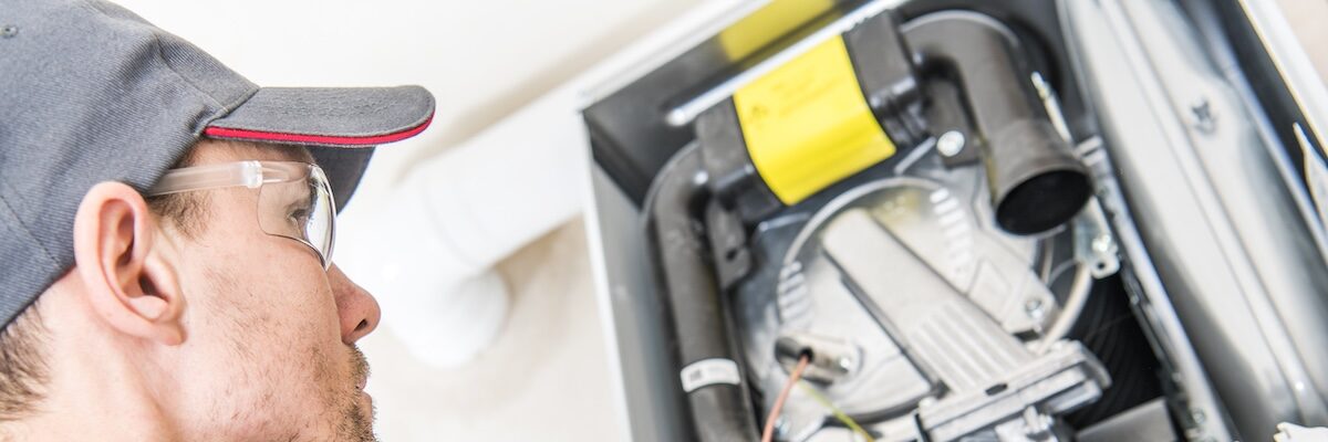 Technician and the Heater Issue. Caucasian Worker Looking Inside Central Gas Heater Trying to Fix the Problem.