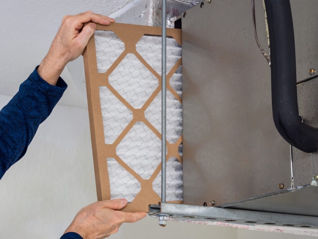 best furnace filters HVAC service technician changing dirty indoor air filter in residential heating and air conditioning system. Home air duct ventilation system maintenance for clean air.
