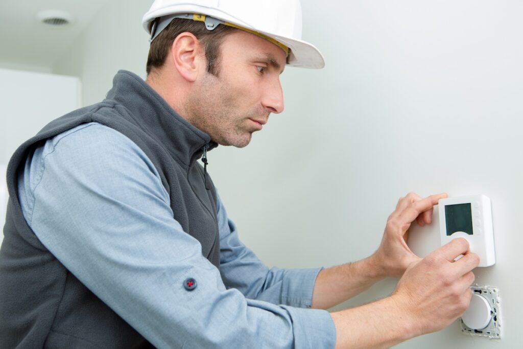 thermostat replacement male worker installing thermostat