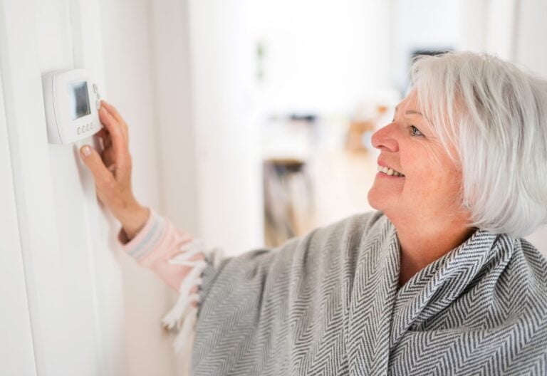 woman adjusting thermostat