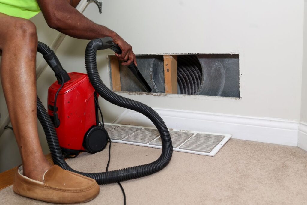 air duct cleaning cost worker using vacuum to clean hole
