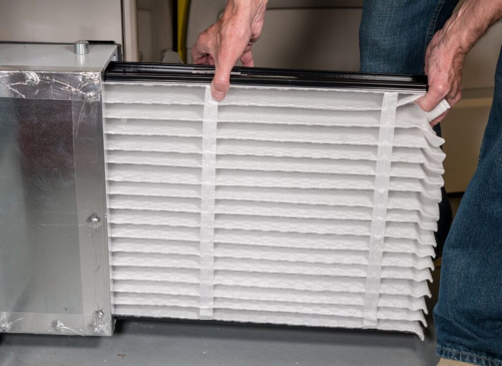 dirty air filter symptoms man replacing clean inside basement